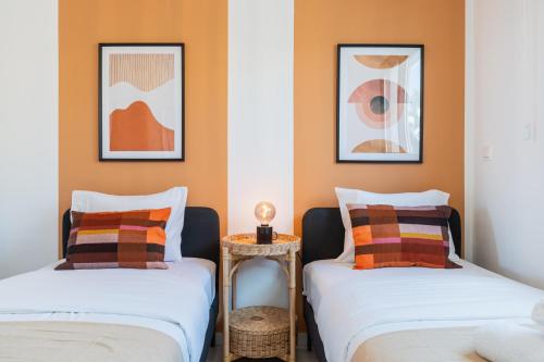 two beds in a room with orange walls at Vervana 2-Bedroom Apartment in Larnaca