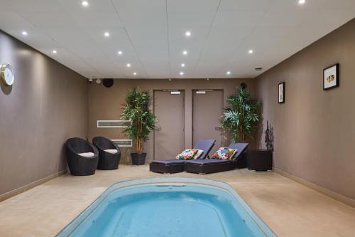 a swimming pool in a room with chairs and a couch at Appart Hotel Odalys City Paris XVII in Paris