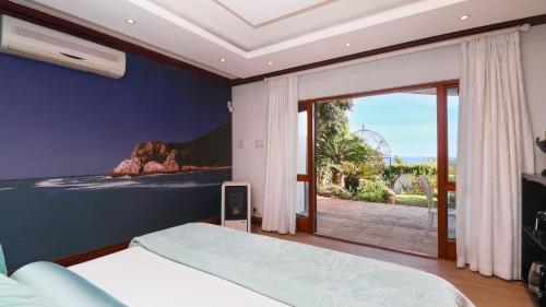 a bedroom with a bed and a sliding glass door at Knysna Pearl View Guest House in Knysna