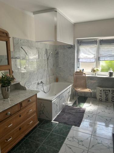 a bathroom with a tub and a chair in it at geschmackvoll eingerichtete Wohnung in mediterranem Flair in Sponheim