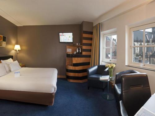 a hotel room with a bed and a chair at Swissôtel Amsterdam in Amsterdam