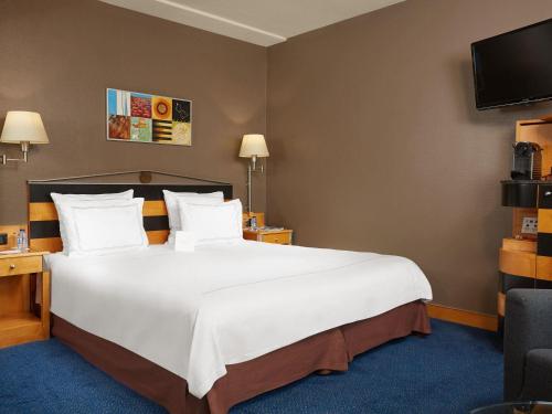 a hotel room with a large bed and a tv at Swissôtel Amsterdam in Amsterdam