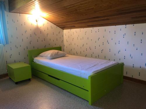 een kleine slaapkamer met een groen bed en een lamp bij Ciboulette 2 in La Clusaz
