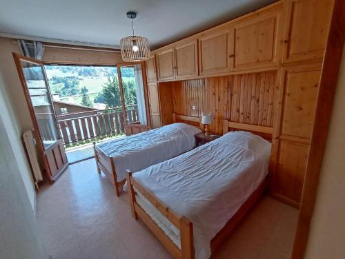 een slaapkamer met twee bedden en een groot raam bij Clair de Lune 2 in La Clusaz