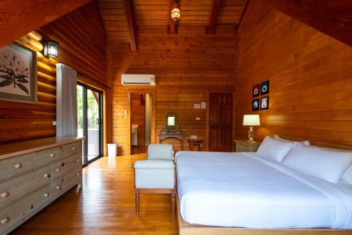 a bedroom with a large white bed and a chair at Monlada Khaoyai in Mu Si