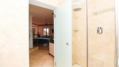 a bathroom with a glass shower and a kitchen at Knysna Pearl View Guest House in Knysna