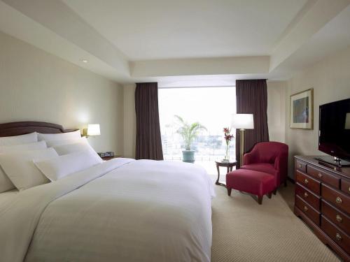 a bedroom with a large white bed and a red chair at Swissotel Lima in Lima