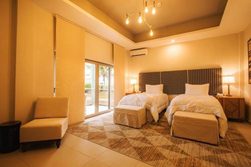 una camera con due letti e una sedia di AnoMansa Beach Resort at Elmina Bay a Elmina