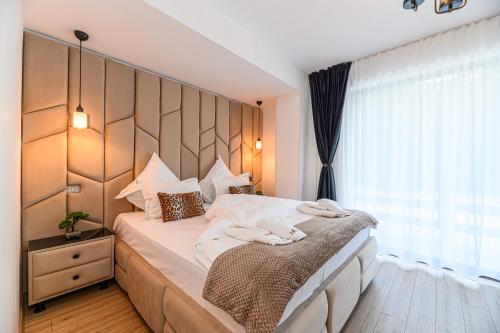 a bedroom with a large bed with a wooden headboard at Ama Garden Spa Apartment Busteni in Buşteni