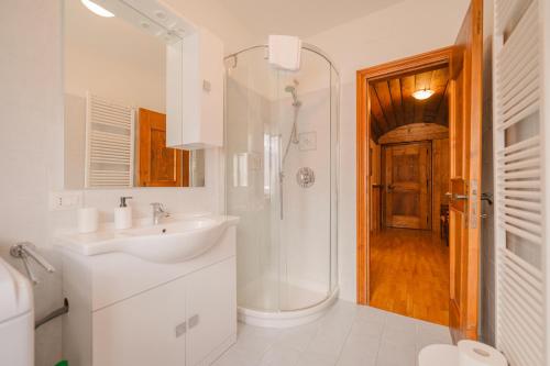een witte badkamer met een wastafel en een douche bij Casa Verocai - Mountain View Terrace & Parking in Cortina dʼAmpezzo