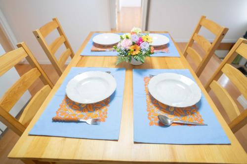 a wooden table with two plates and a vase of flowers at 佐世保　貸切小さな一軒家　GUEST HOUSE　楽楽 Luck-Luck in Sasebo