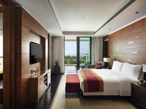 a hotel room with a bed and a television at Raffles Hainan Clear Water Bay in Sanya
