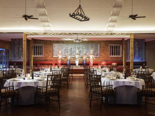 a banquet hall with tables and dancers on the stage at Raffles Grand Hotel d'Angkor in Siem Reap