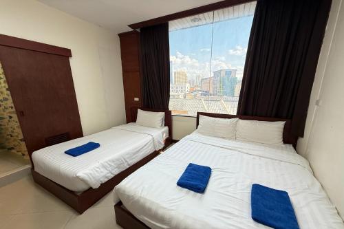 two beds in a hotel room with blue towels on them at Scala Hostel in Bangkok