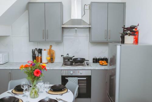 a kitchen with white cabinets and a table with a vase of flowers at Perfectly Located City Centre Apartments in Reading