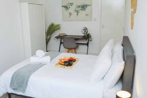 a white bed with a tray of fruit on it at Perfectly Located City Centre Apartments in Reading