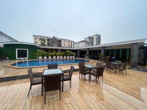 a patio with tables and chairs and a swimming pool at Presken Residence in Ikeja