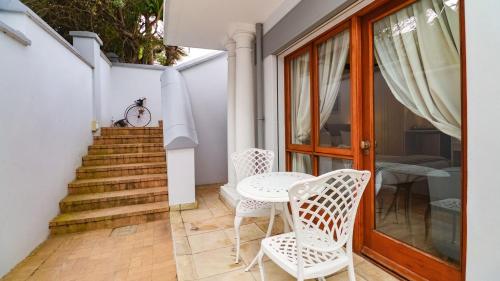 a patio with a table and chairs and a staircase at Knysna Pearl View Guest House in Knysna