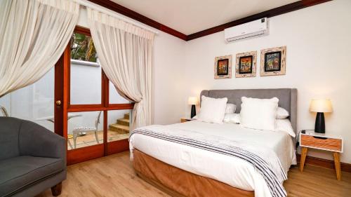 a bedroom with a bed and a chair and a window at Knysna Pearl View Guest House in Knysna
