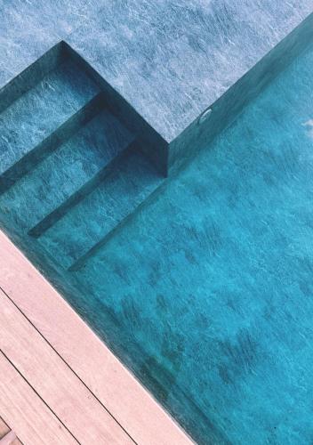 una piscina di acqua azzurra e limpida con un ponte di legno di Villa Anjo a Zonza