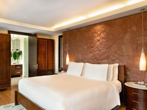 a bedroom with a large bed and a stone wall at Raffles Seychelles in Baie Sainte Anne