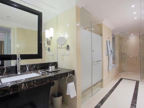 a bathroom with a sink and a mirror and a shower at Raffles Makati in Manila