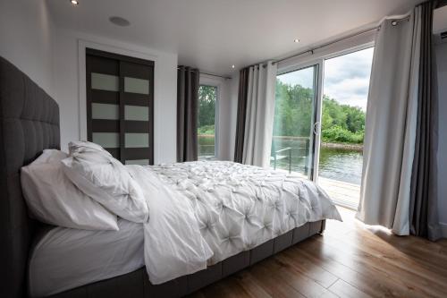 a bedroom with a large bed and a large window at Yacht Club de Trois-Rivières 1 - Maison flottante in Trois-Rivières