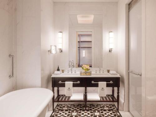 a white bathroom with a sink and a tub at Raffles Singapore in Singapore