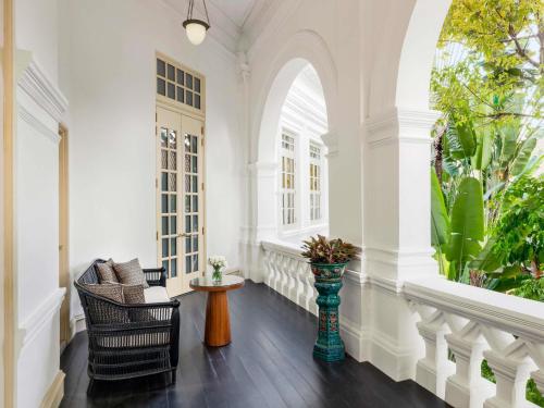 a living room with white walls and a large window at Raffles Singapore in Singapore