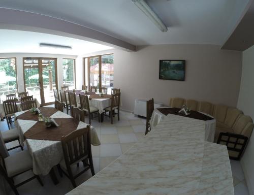 a dining room with tables and chairs and windows at Ивелия Къща за гости in Dospat