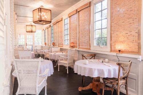 a restaurant with white tables and chairs and windows at The Edenton Collection-The Granville Queen Inn in Edenton