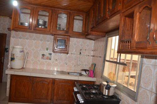 a kitchen with wooden cabinets and a stove top oven at VICTOR & VICTORY GUEST HOUSE DAMAS-RAIL OBOBOGO Source in Yaoundé