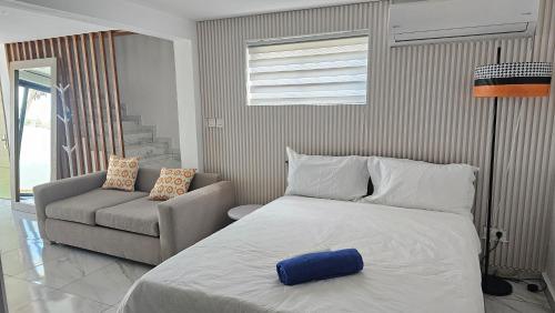 Un dormitorio con una cama grande y un sofá. en Studio Furnished - 1Bed - Pool - Beach - Grand Bay, en Grand Baie