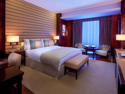 a hotel room with a large bed and a desk at La Cigale Hotel Managed by Accor in Doha