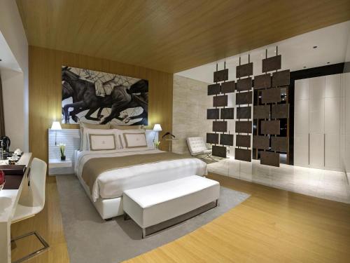 a bedroom with a large bed and a large painting on the wall at La Cigale Hotel Managed by Accor in Doha