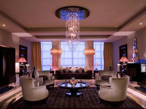 a living room with a chandelier and a couch and chairs at La Cigale Hotel Managed by Accor in Doha