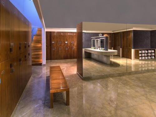 a bathroom with a bench and a sink in a room at La Cigale Hotel Managed by Accor in Doha