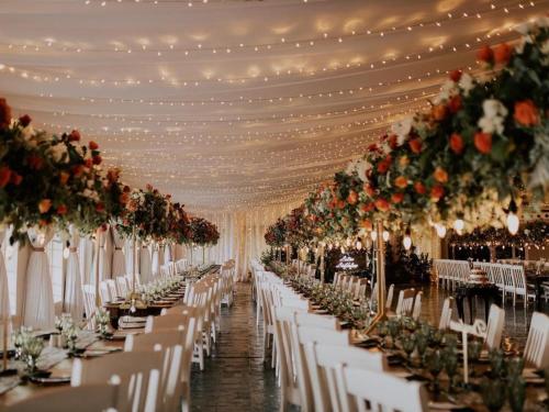 a row of tables with white chairs and flowers at Platrand Lodge 