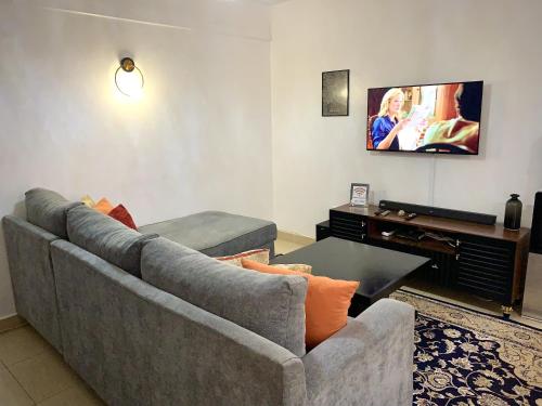 a living room with a gray couch and a piano at Valentine's Suite in Nairobi