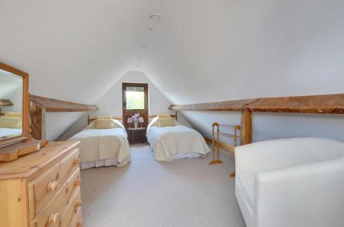 a attic bedroom with two beds and a mirror at Dairy Cottage in Wadhurst
