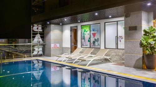 a pool with lounge chairs next to a building at Paradise Hotel - Pool , Sky Lounge , Gym - Massage & Wellness in Cat Ba