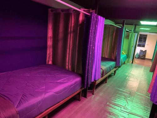a room with two beds with purple curtains at RoXx Social Hostel in Bangkok