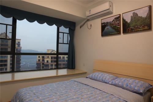 a bedroom with a bed and two large windows at Zhangjiajie 72 Wonder Tower Neighbour's House in Zhangjiajie