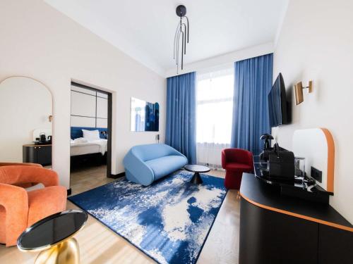 a living room with a blue chair and a tv at TRIBE Riga City Centre in Rīga