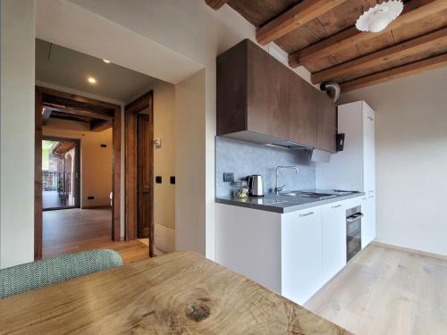 a kitchen with white cabinets and a wooden table at Il Ronchetto in Cunardo