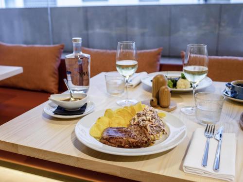 a table with a plate of food and glasses of wine at Mercure Fátima in Fátima