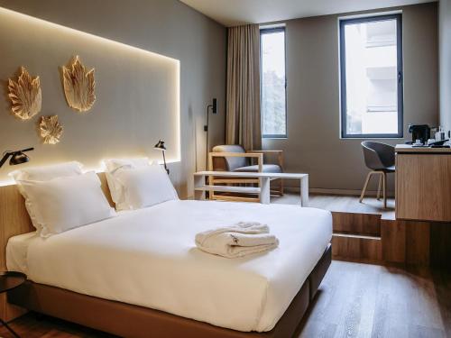 a hotel room with a white bed and a desk at Mercure Fátima in Fátima