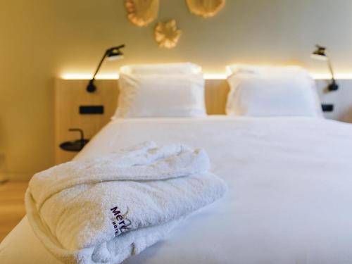 a stack of towels sitting on top of a bed at Mercure Fátima in Fátima