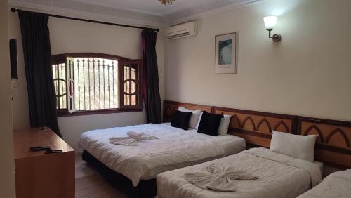 a hotel room with two beds and a window at FEKHARA Country Club in Marrakech