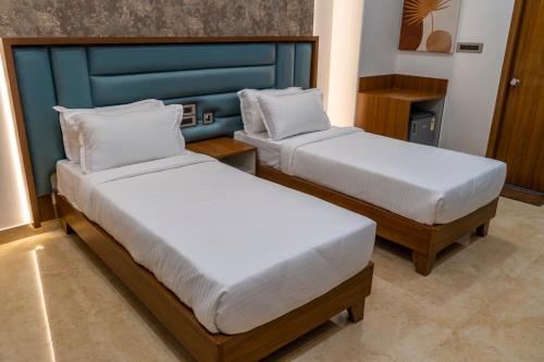 a room with two beds and a blue headboard at Hotel K Fortune in Kurnool